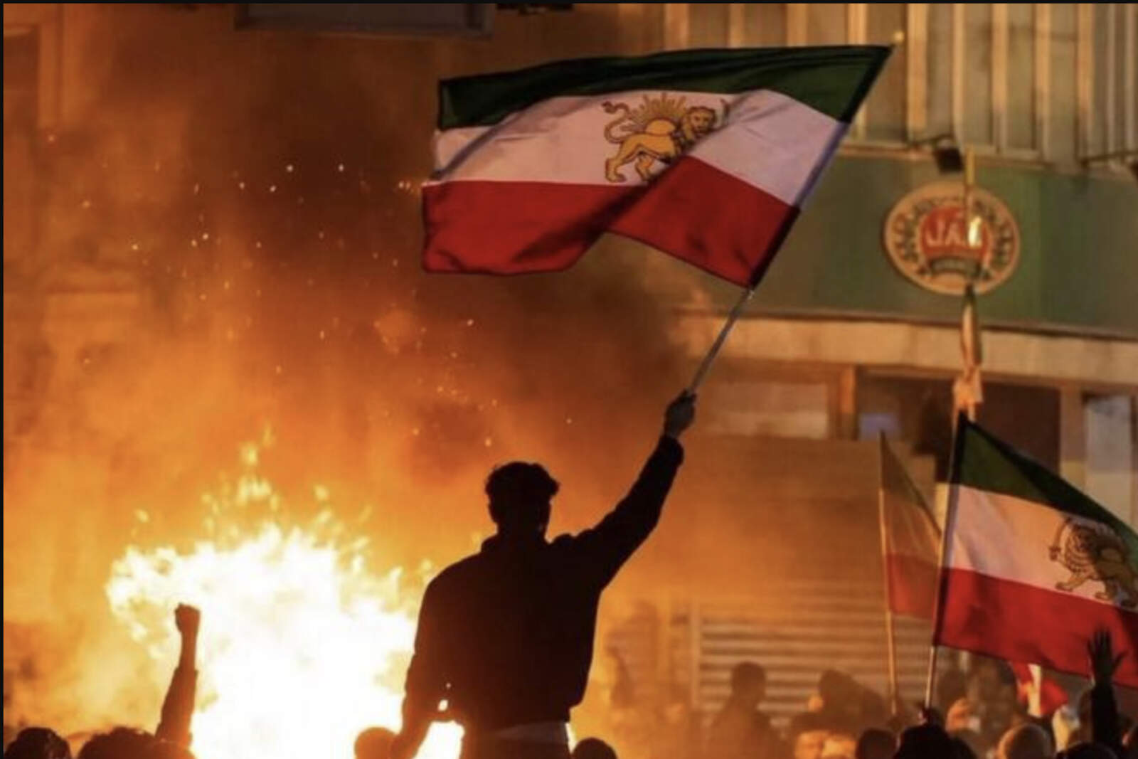 Manifestantes levantan banderas iraníes históricas, en rechazo al régimen islámico.