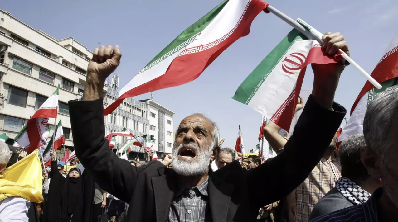 Protester in Tehran raises the Iranian flag during a mobilization amid regional escalation