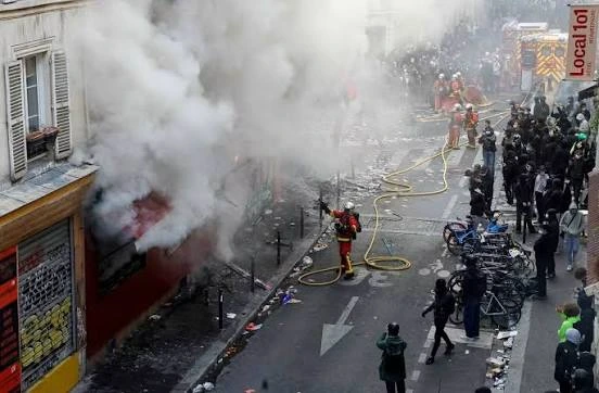 Bomberos franceses apagando un comercio que habia siendo incendiado por extremistas de izquierda